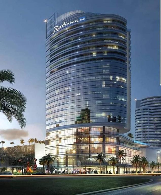 a large building with palm trees in front of it at Oceans Apartments Balcony Suites in the Radisson Blu Hotel Building Tower,Durban,Umhlanga in Durban
