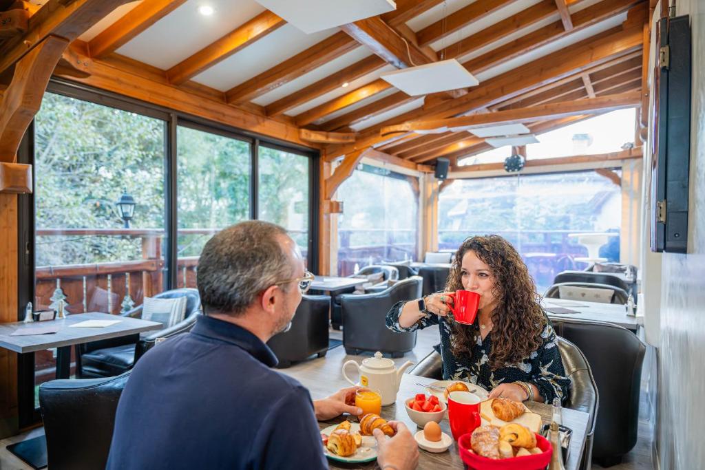 a man and a woman sitting at a table eating food at Logis Hôtel et Spa Le Christiania in La Salle-les-Alpes