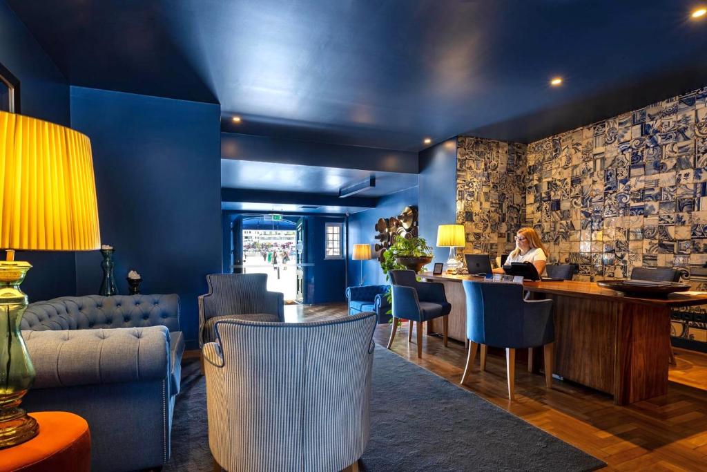 a woman sitting at a bar in a blue room at Villa Cascais Boutique Hotel in Cascais