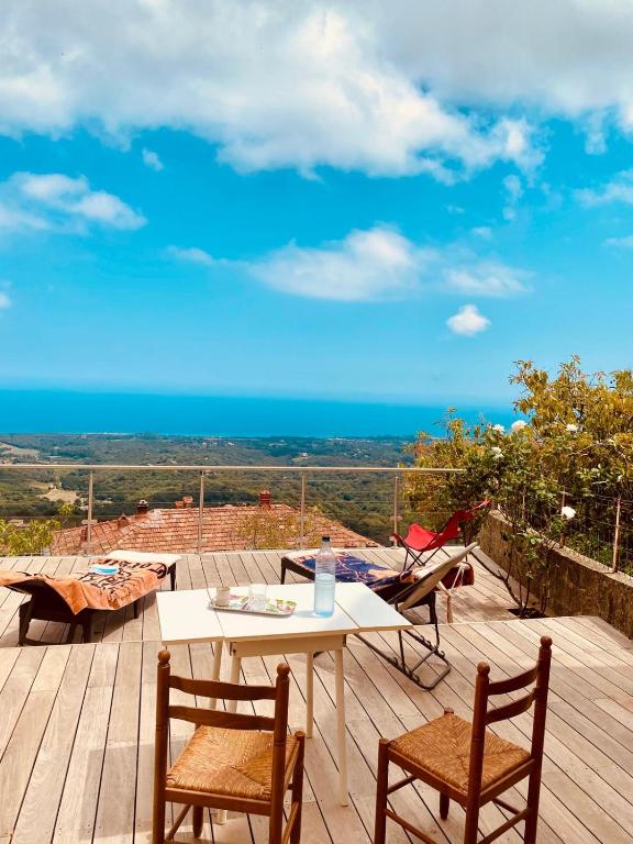 - une table et des chaises sur une terrasse en bois donnant sur l'océan dans l'établissement Villa tout confort, vue mer exceptionnelle, à Cervione, à Cervione