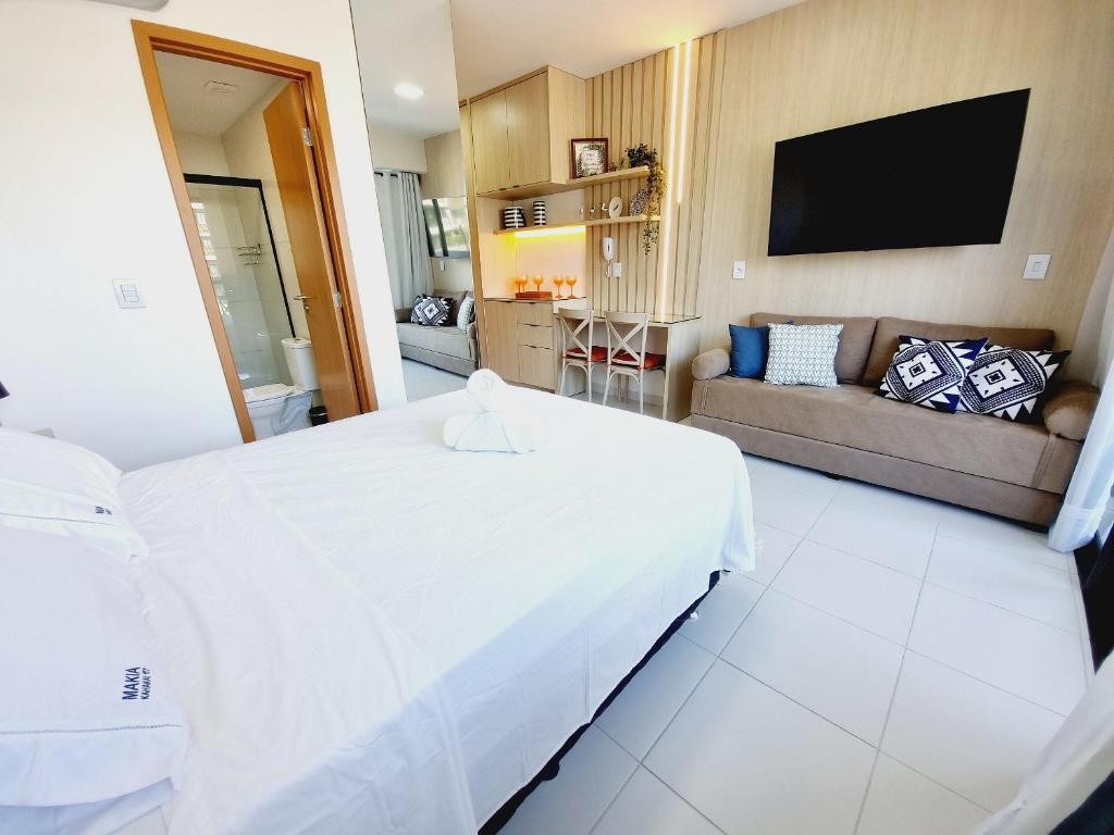 a bedroom with a large white bed and a couch at Flat em Muro Alto - Porto de Galinhas - MAKIA B117 - By Anfitrião Legal in Porto De Galinhas