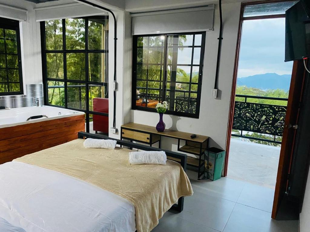 a bedroom with a bed and a tub and windows at Hotel Curazao Natural Living in Cocorná