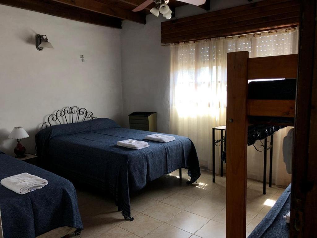 een slaapkamer met een bed met blauwe lakens en een raam bij Hostería Michel in Villa Gesell