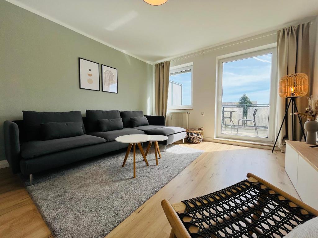 a living room with a black couch and a table at Modern 2-Bedroom Apartment Near Messe 2-4 Guests in Augsburg