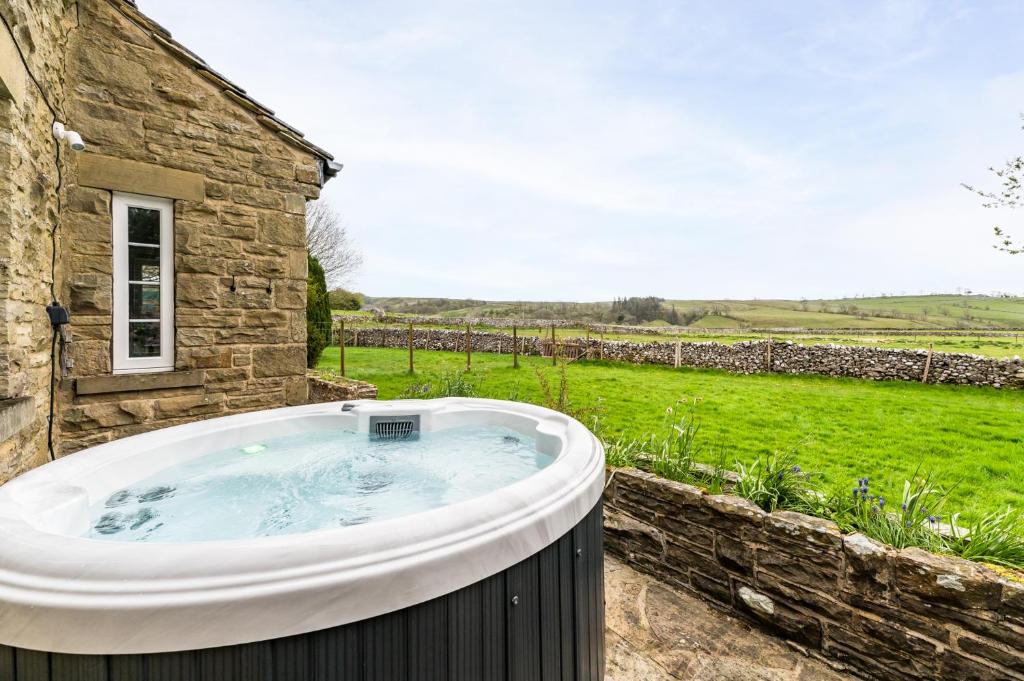 a hot tub in front of a stone building at Central Malham Wellbeing Escape, 5-bed house with yoga studio in Malham