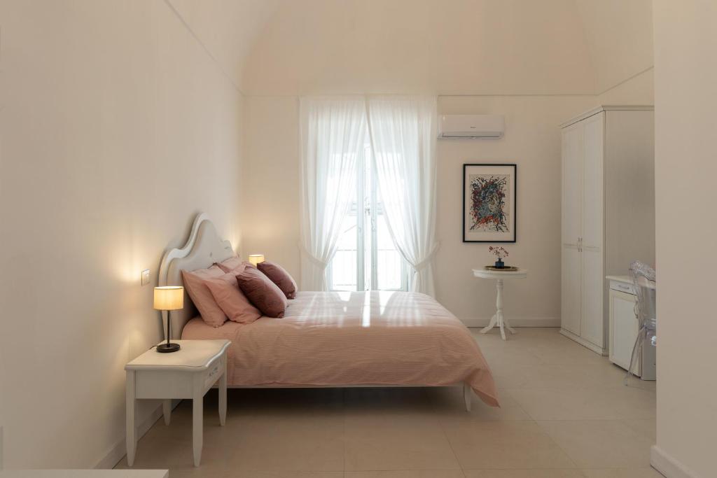 a white bedroom with a bed and a window at Dimora Margherita in Caserta