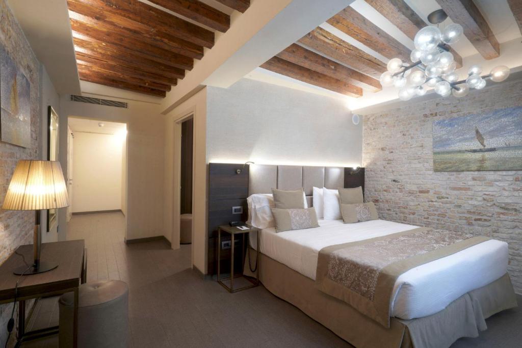 a bedroom with a large bed and a brick wall at Hotel Aquarius Venice - Ascend Collection in Venice