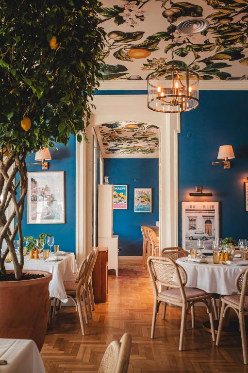 a restaurant with blue walls and tables and a tree at Villa Cascais Boutique Hotel in Cascais