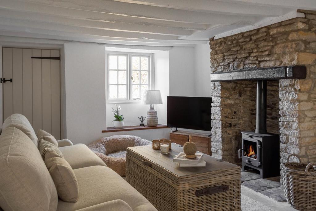 un salon avec un canapé et une cheminée dans l'établissement Banksia Cottage, à Enstone