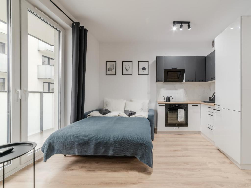 a bedroom with a bed and a kitchen at City Spot Łódź by Aparo - Manufaktura, Nowy Apartament, PlayStation, Miejsce do Pracy, Winda, Balkon in Łódź