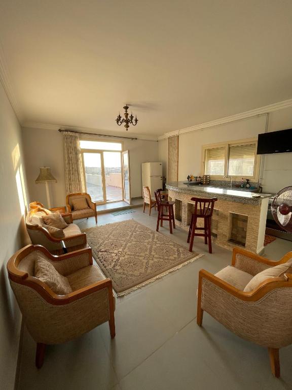 a large living room with chairs and a kitchen at The Grand Penthouse in Cairo