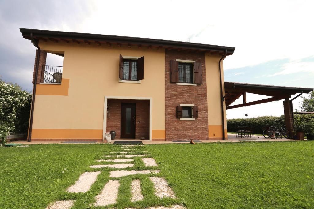 une maison avec une pelouse verte devant elle dans l'établissement B&B L'Upupa, à Bussolengo