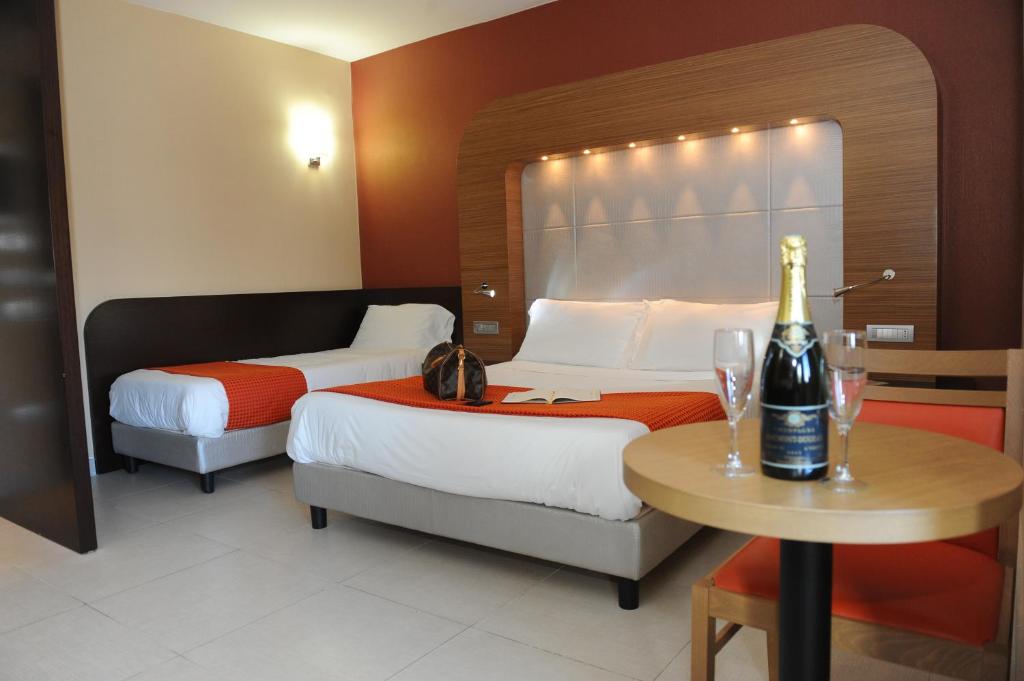 una habitación de hotel con 2 camas y una botella de vino en una mesa en Hotel Ristorante La Campagnola, en Cassino