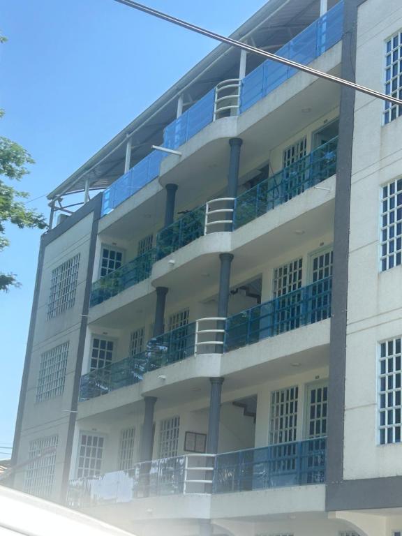biały budynek z niebieskimi balkonami w obiekcie Edificio Arrecife w mieście Cali