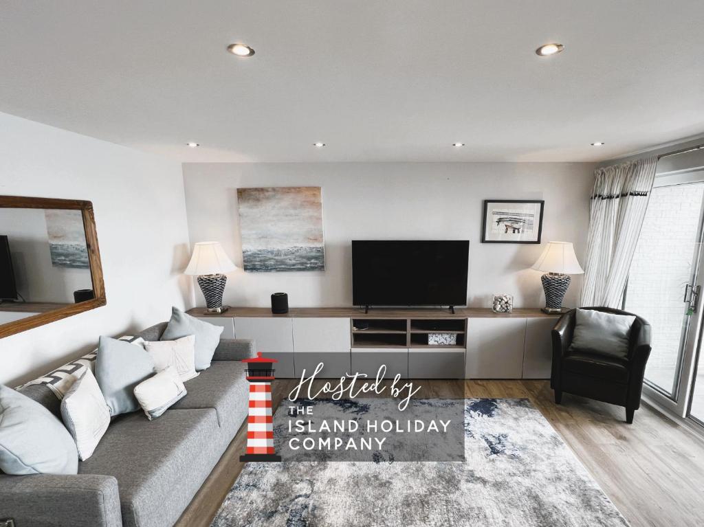 a living room with a couch and a flat screen tv at 25 Breakwaters - Beach Hut is Included with this Dog Friendly Lux Apartment with Balcony, Stunning Sea Views over to Culver Cliffs & Free Parking in Sandown
