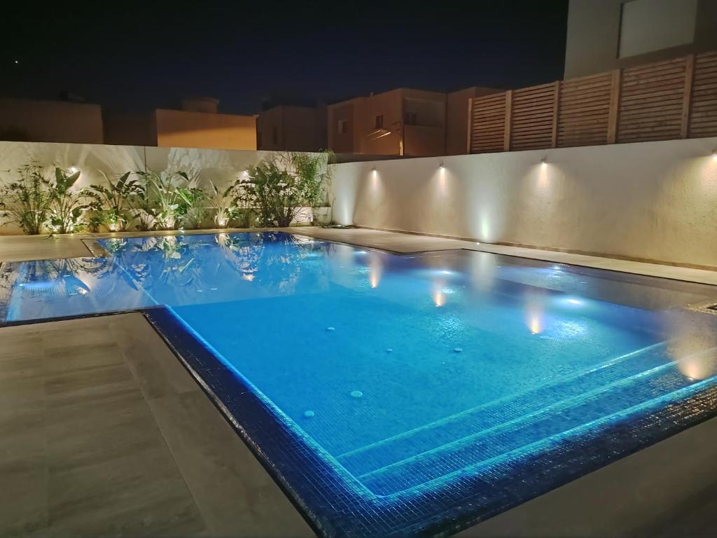 Una gran piscina con agua azul por la noche. en Coquet appartement avec piscine à 10min de l'aéroport Tunis - family only, en La Soukra