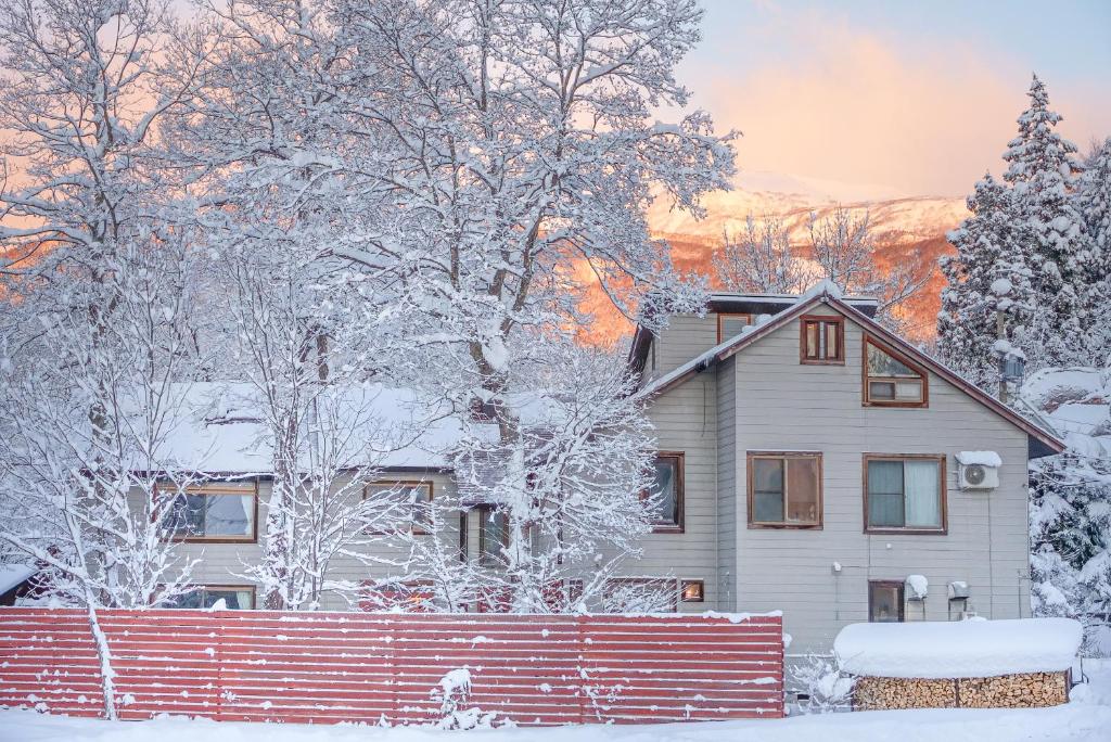 une maison avec des arbres enneigés et une clôture dans l'établissement Kawa Mountains Hakuba, à Hakuba