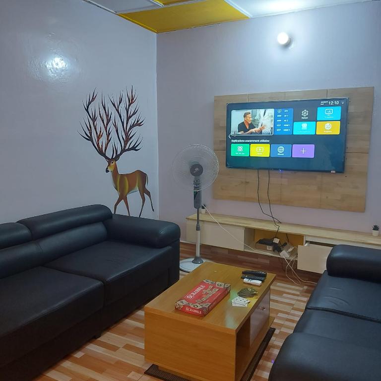 a living room with a couch and a flat screen tv at Le séjour fruité in Ouidah