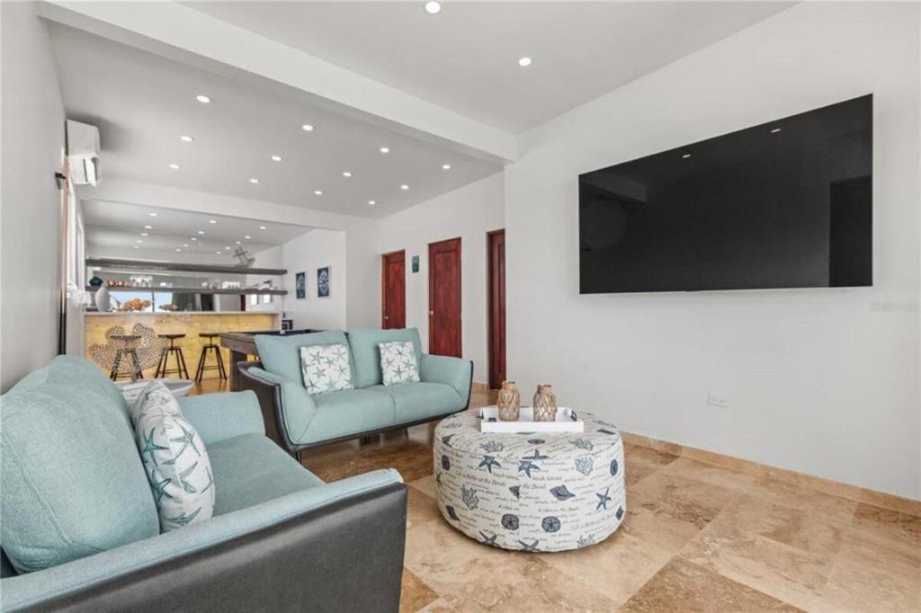 a living room with two blue chairs and a tv at Just a few minutes walking to the Beach Club in Sabana