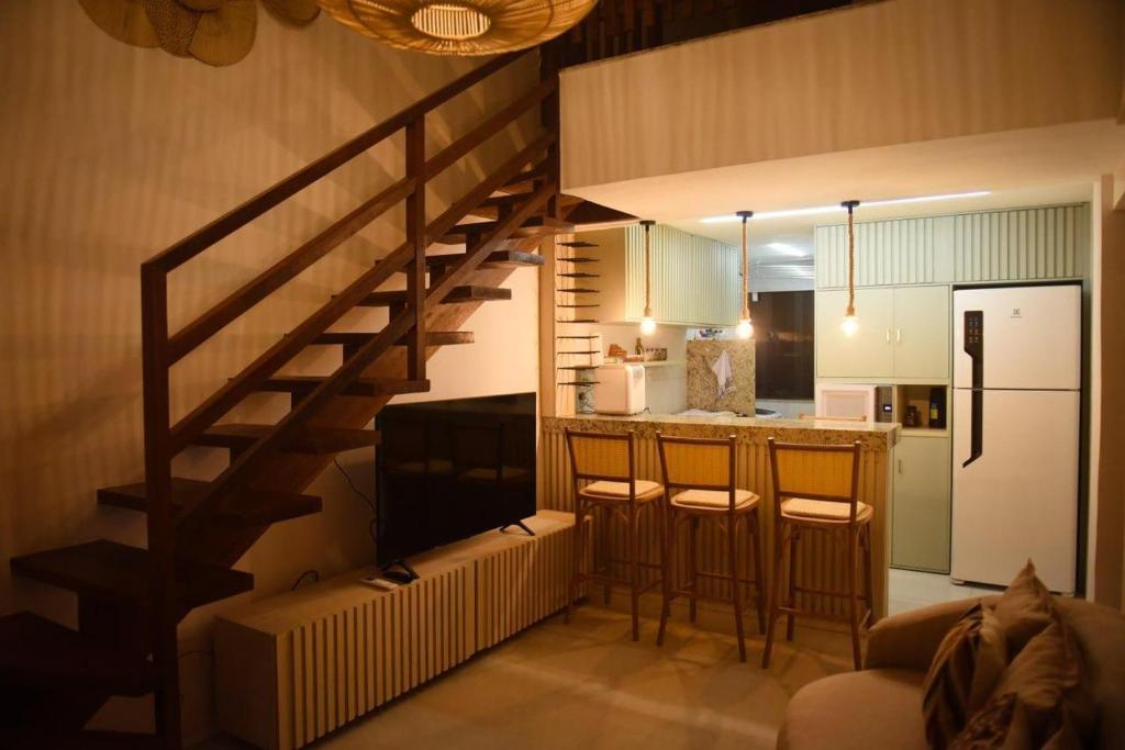 a living room with a staircase and a kitchen at GUARAJUBA TIE 4 Quartos DUPLEX DE LUXO in Camacari