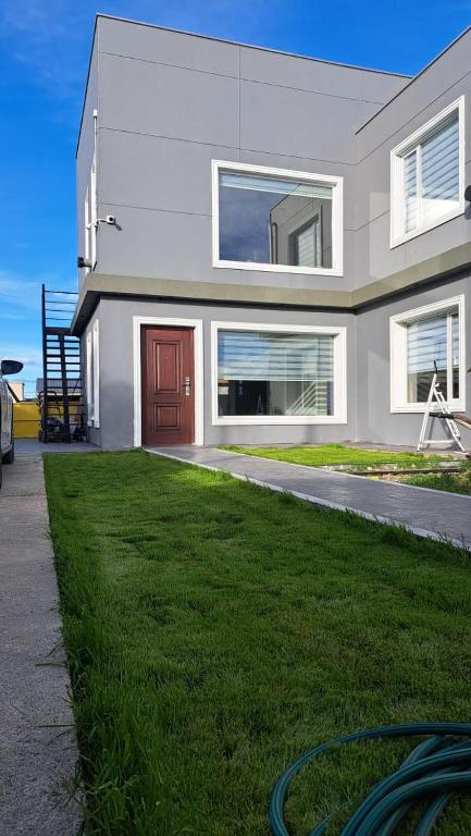 a house with a grassy yard in front of it at Mate 2 in Río Gallegos