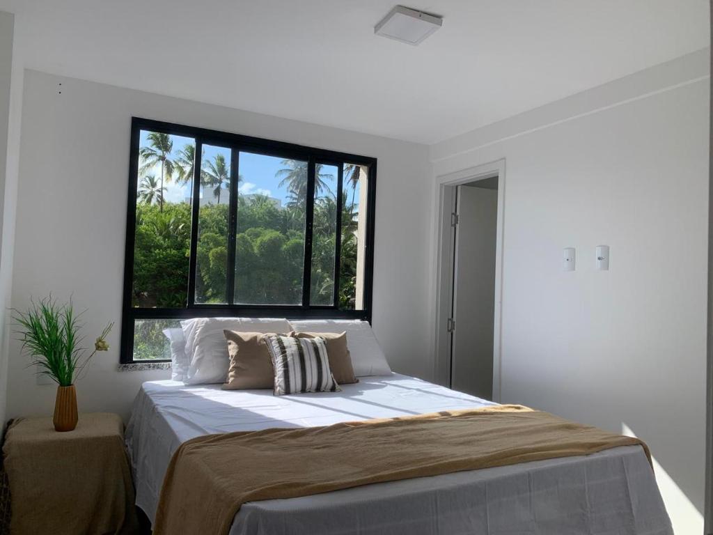 una camera da letto con un letto grande con una finestra di Apartamento Beira-mar orla sul a Ilhéus