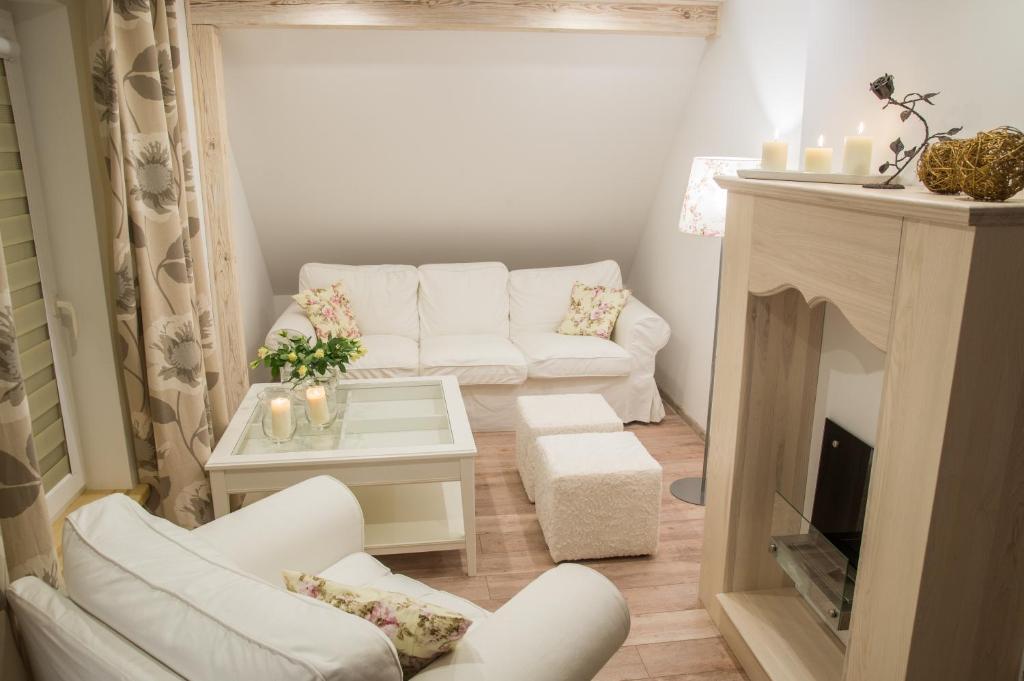 a living room with white furniture and a fireplace at Dom nad jeziorem Mikołajki in Mikołajki