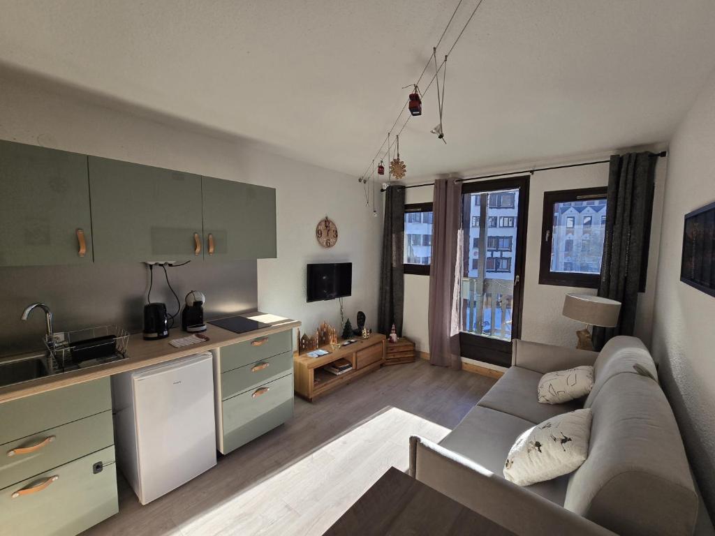 Il comprend un grand salon avec un canapé et une cuisine. dans l'établissement Studio avec balcon vue MontBlanc et parking gratuit le nid daigle, à Chamonix-Mont-Blanc