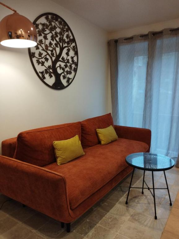 - un canapé brun dans le salon avec une table dans l'établissement gîte Couleur Cuivre, à Cerdon