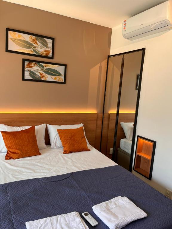 um quarto com uma cama com almofadas laranja e um espelho em Studio moderno e charmoso no melhor lugar da Barra em Salvador