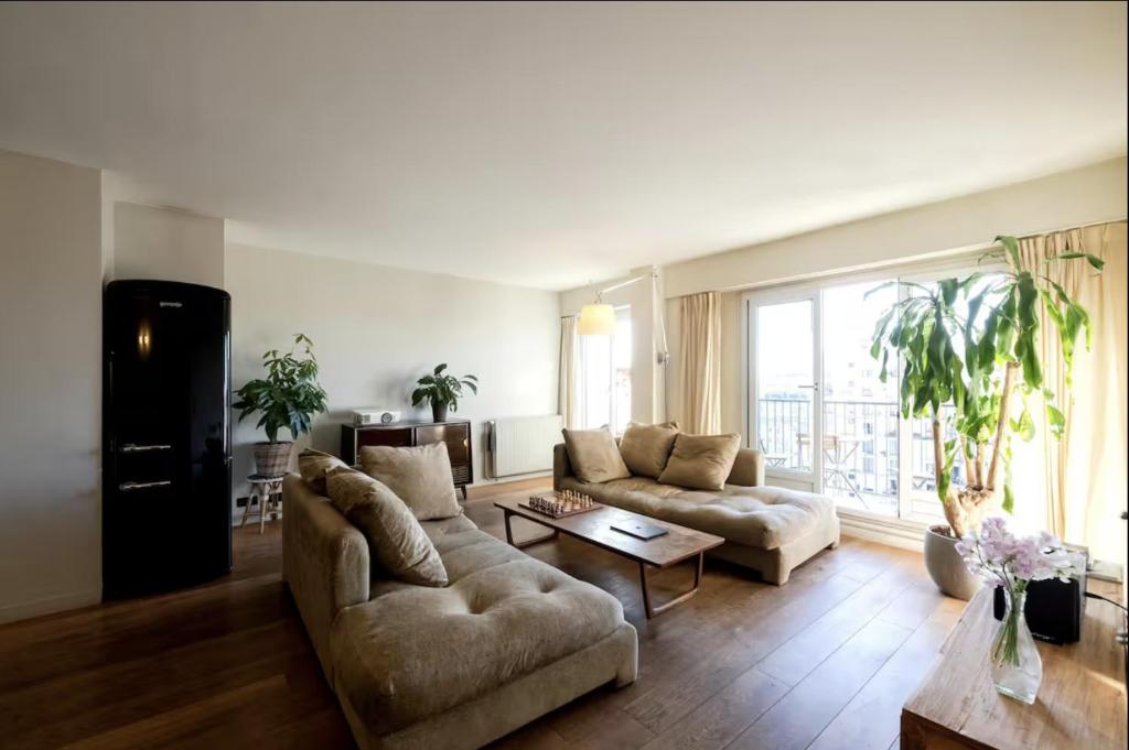 un salon avec deux canapés et une grande fenêtre dans l'établissement Amazing view, beautiful flat, swimming pools, secure parking, à Paris