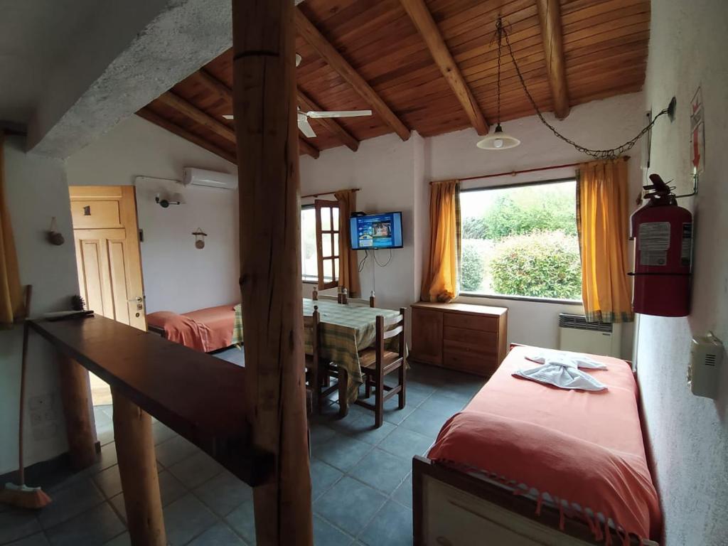 Un dormitorio con dos camas y una mesa y una ventana. en Complejo de cabañas en Nono, en Nono