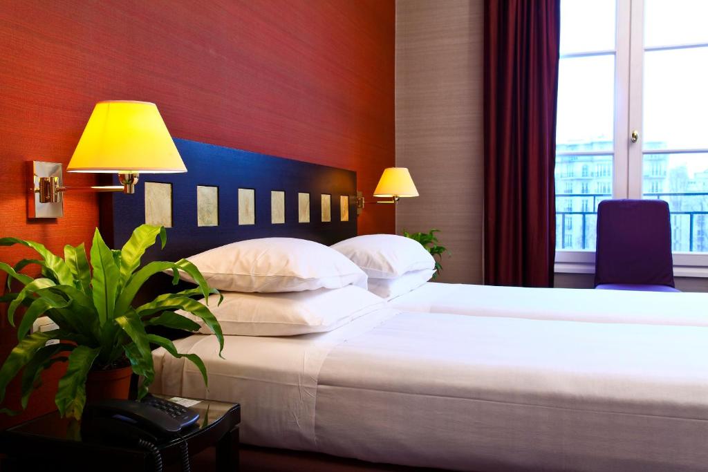 ein Hotelzimmer mit einem Bett mit weißer Bettwäsche und Kissen in der Unterkunft Hotel De La Jatte in Neuilly-sur-Seine
