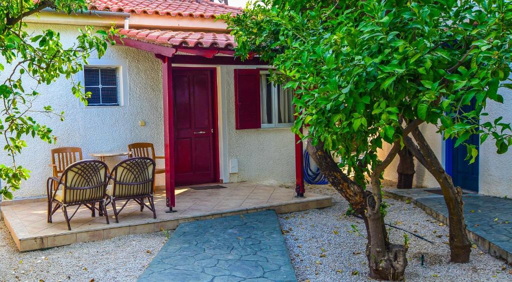 a table and chairs in front of a house with a red door at Green Village in Xylokastro