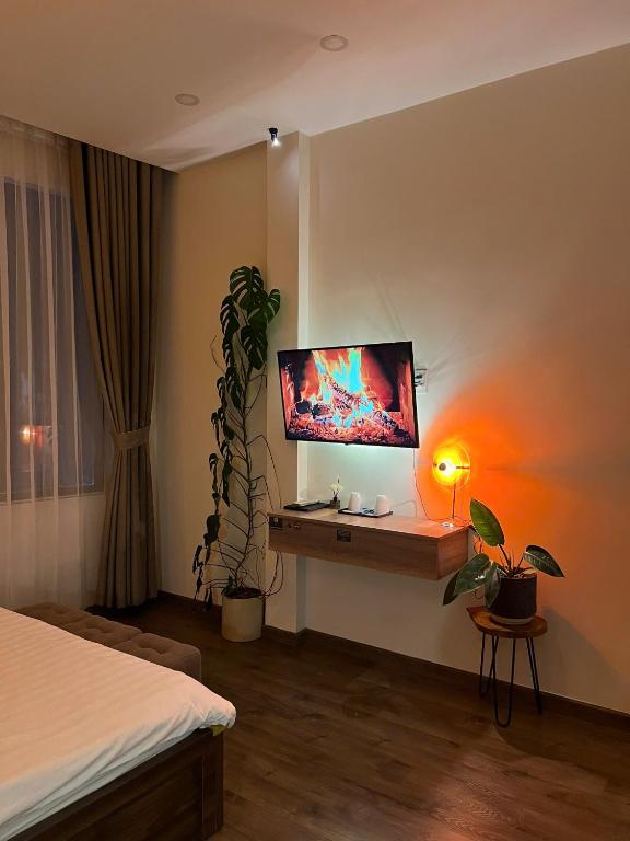 a bedroom with a bed and a desk with a tv on the wall at Villa Délight House “Stay&Chill” in Da Lat