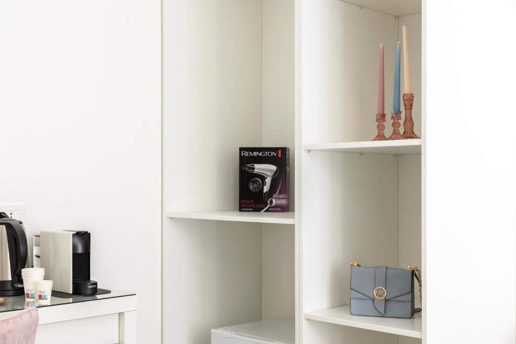 a room with white shelves with a microwave and a candle at Maddalena Rooms - Eja Sardinia in Cagliari