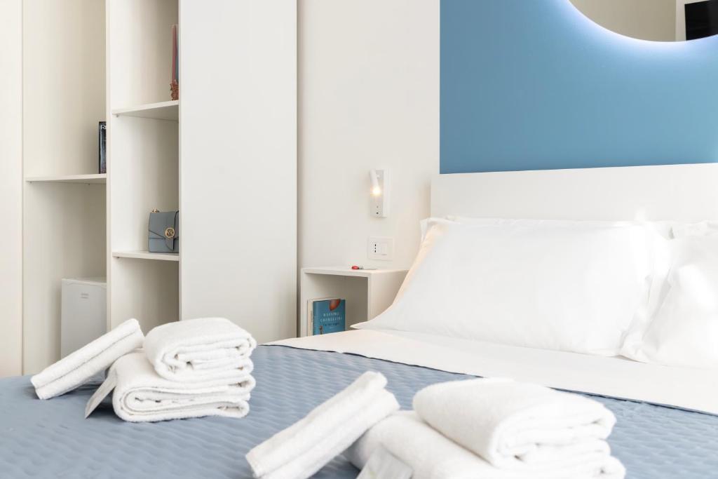 a bed with white towels on a blue blanket at Maddalena Rooms - Eja Sardinia in Cagliari