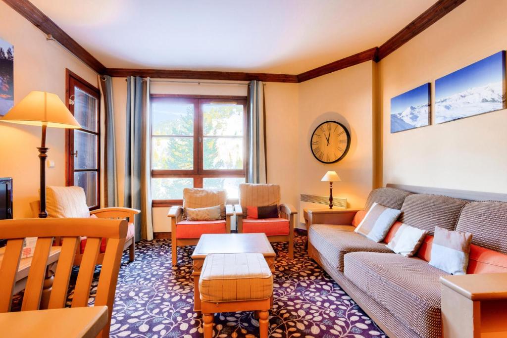 - un salon avec un canapé, des chaises et un réveil dans l'établissement Résidence Les Arcs 1950 Le Village - maeva Home - Appartement 3 pièces 6 personnes - Sélection MAE-8281, à Arc 1950