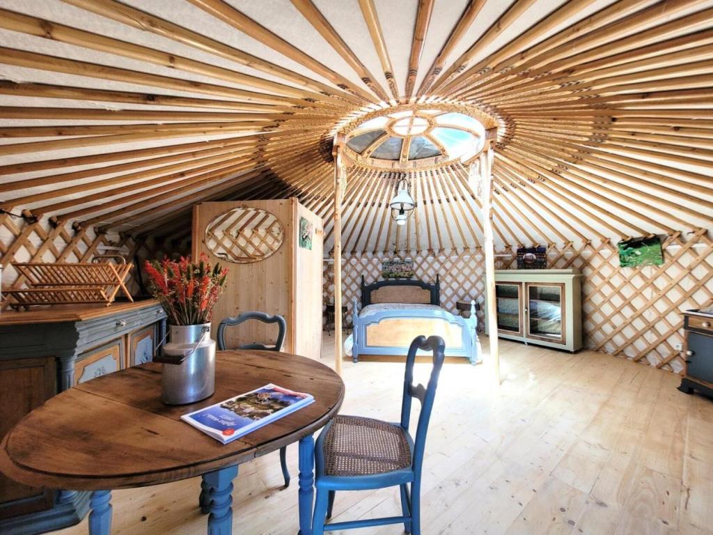 Cette chambre dispose d'un plafond en bois avec une table et un lit. dans l'établissement Gîte de France La yourte joulebois - Gîte de France 2 personnes MAE-6961, à Saillac