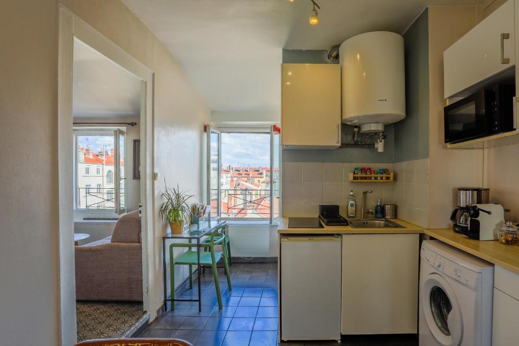 une cuisine avec un évier et une table avec des chaises dans l'établissement Lyon Premium- Nid Cosy, à Lyon