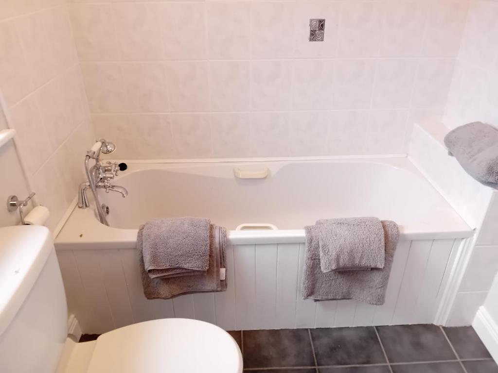 a bathroom with a tub and a toilet and towels at Forest Lodge in Drumahayre