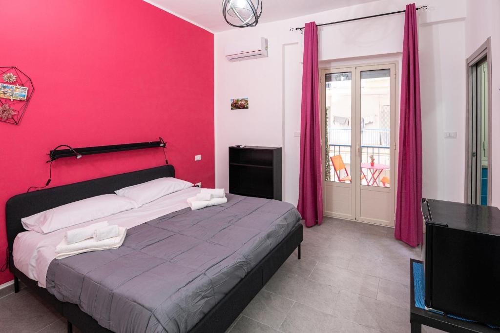 Un dormitorio con una cama con una pared rosa. en Splendori Rooms, en Palermo