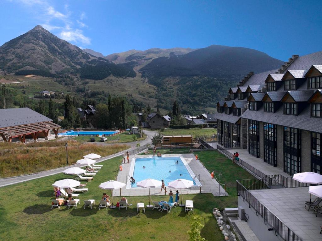 a resort with a swimming pool and mountains in the background at Apartamentos HG Cerler in Cerler