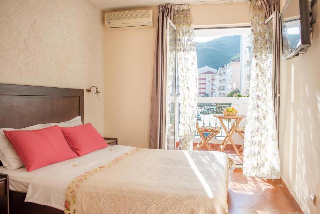a bedroom with a bed with red pillows and a window at Hotel Villa Perla Di Mare in Budva
