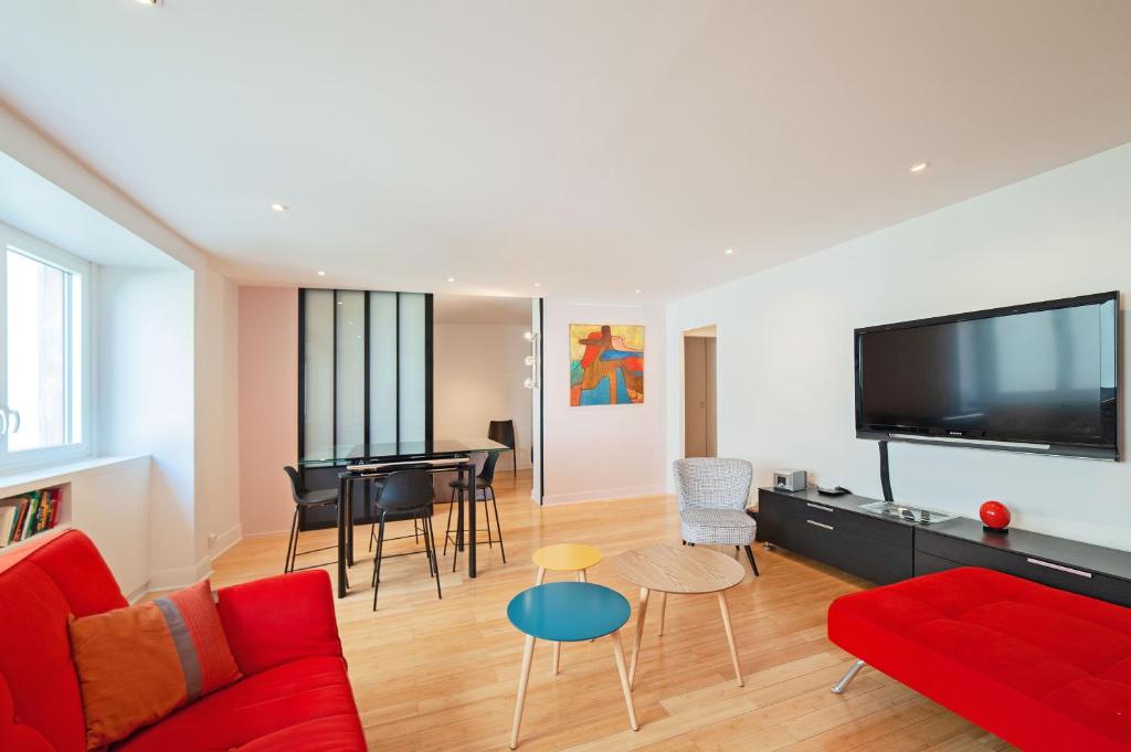 Il comprend un salon doté d'un canapé rouge et d'une télévision à écran plat. dans l'établissement large pleasant studio alcove in center, à Paris
