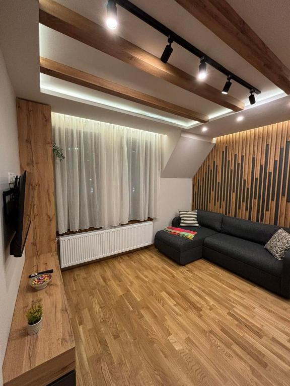 a living room with a black couch and a window at Šumska staza Divčibare apartmani in Divčibare