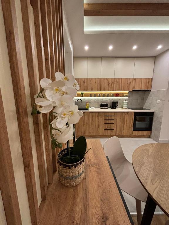 a kitchen with a table with a vase with white flowers at Šumska staza Divčibare apartmani in Divčibare