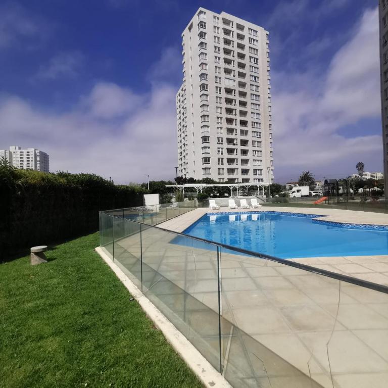 a swimming pool with a tall building in the background at Dpto Playa Casino Marina Sol in Coquimbo