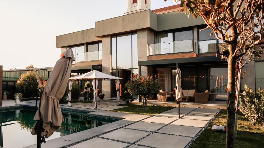 een gebouw met een zwembad en een parasol ervoor bij Diwine Spa House Fruška Gora in Irig