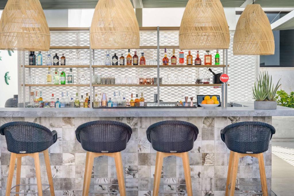 a bar with three wicker stools in front of a counter at AC Hotel by Marriott Tenerife in Santa Cruz de Tenerife